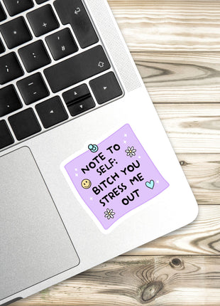 A sticker with a humorous message is placed on a laptop keyboard.