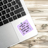A sticker with a humorous message is placed on a laptop keyboard.