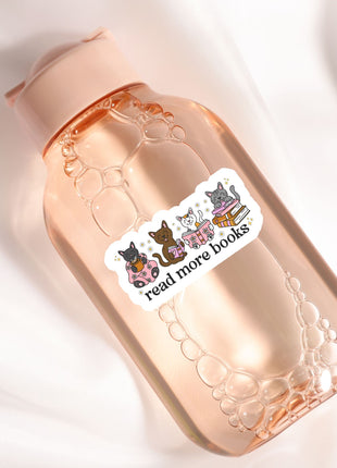 A pink water bottle with a sticker on it, featuring a group of cats and the text "read more books".