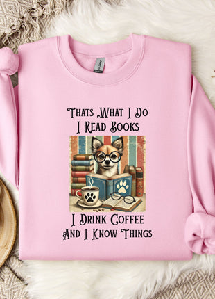 A pink sweatshirt with a graphic design of a dog wearing glasses and holding a book, along with text that says "Thats what I do I read books I drink coffee and I know things".