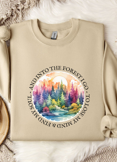 A beige sweatshirt with a colorful forest scene printed on it, along with a mug, a snowflake, and some cotton balls, all arranged on a white fur rug.