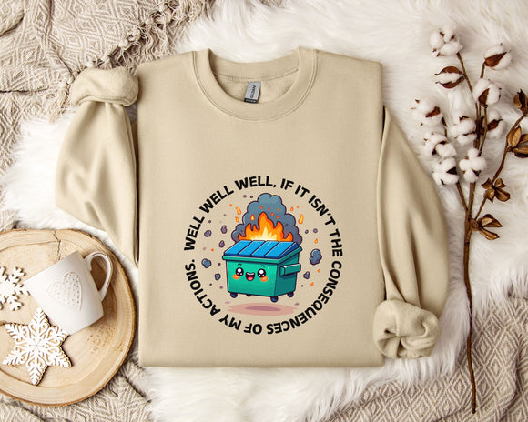a beige sweatshirt with a graphic design depicting a fire-breathing trash can surrounded by flames and smoke. The sweatshirt is placed on a bed with a white blanket and a white mug.