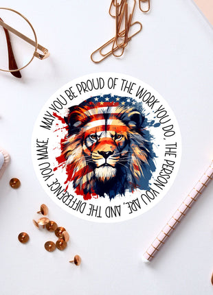 a circular sticker with a lion's face design, surrounded by various office supplies such as pens, paper clips, and a pair of glasses.