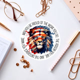 a circular sticker with a lion's face design, surrounded by various office supplies such as pens, paper clips, and a pair of glasses.