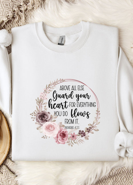 a white t-shirt with a floral design and text printed on it, placed on a bed with a white blanket and a white mug.