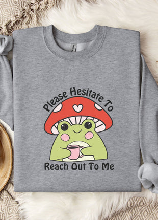 a gray sweatshirt with a mushroom character and text, along with a mug and some white flowers on a bed.