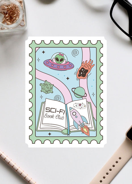 a colorful stamp with a whimsical illustration of a book, a rocket ship, and various other space-themed elements. The stamp is surrounded by various office supplies, including a pair of glasses, a pen, and a notebook.