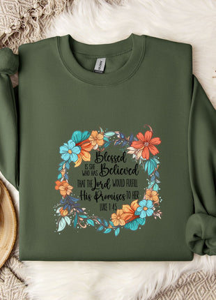 A green sweatshirt with a floral design and text printed on it, along with a mug and some white flowers on a white surface.