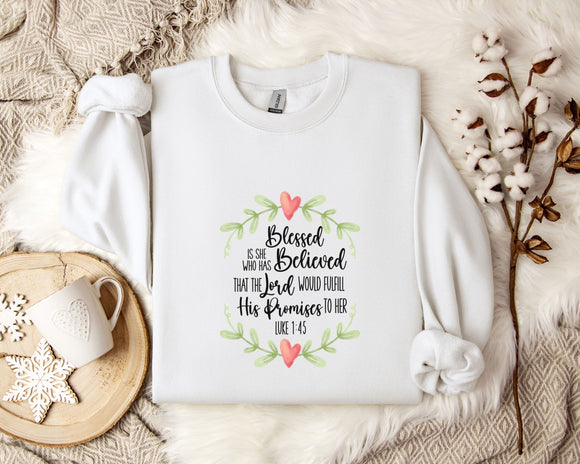 A white t-shirt with a printed text design, a white mug, and some white flowers on a bed with a white blanket.