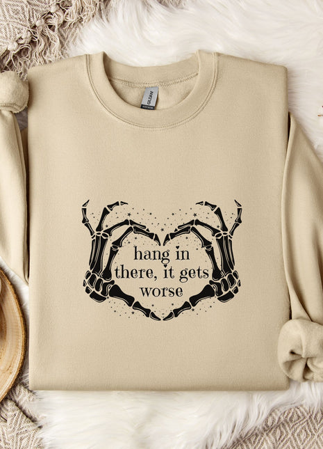 a beige sweatshirt with a graphic design on it, along with a mug, a branch of cotton bolls, and a blanket.
