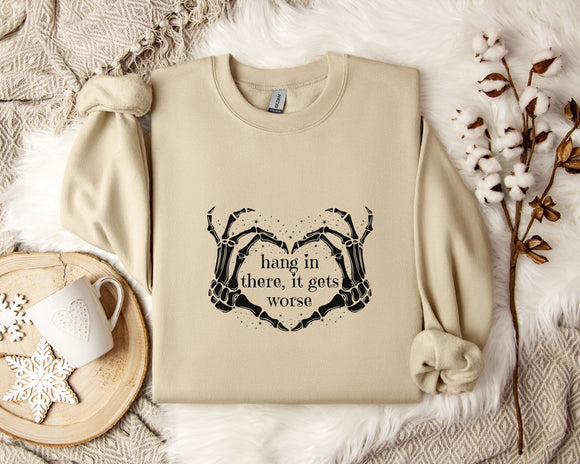 a beige sweatshirt with a graphic design on it, along with a mug, a branch of cotton bolls, and a blanket.