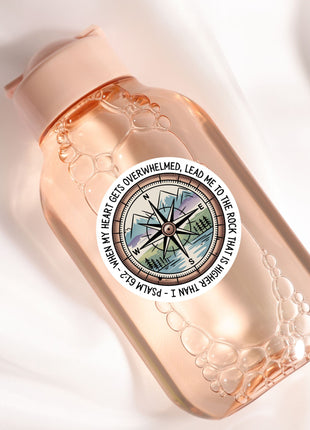 A pink bottle with a compass design and a quote around it.
