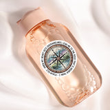 A pink bottle with a compass design and a quote around it.