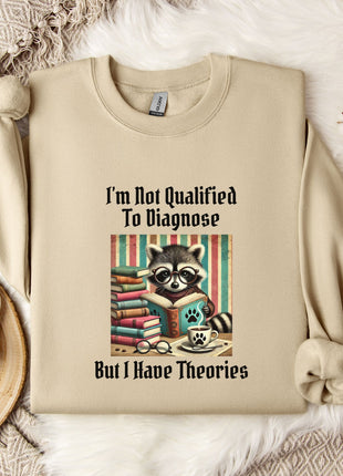a beige sweatshirt with a graphic design of a raccoon reading a book, accompanied by the text "I'm Not Qualified To Diagnose But I Have Theories".