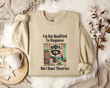 a beige sweatshirt with a graphic design of a raccoon reading a book, accompanied by the text "I'm Not Qualified To Diagnose But I Have Theories".