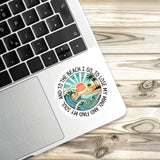 A sticker with a beach scene and a quote is placed on the edge of a laptop keyboard.
