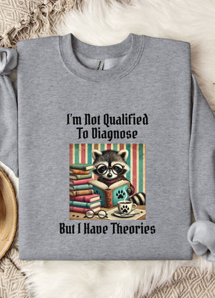 a gray sweatshirt with a graphic design of a raccoon reading a book, accompanied by the text "I'm Not Qualified To Diagnose But I Have Theories".