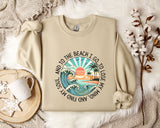 A beige sweatshirt with a graphic design depicting a beach scene, along with the text "And to the beach I go, I lose my soul and my mind".