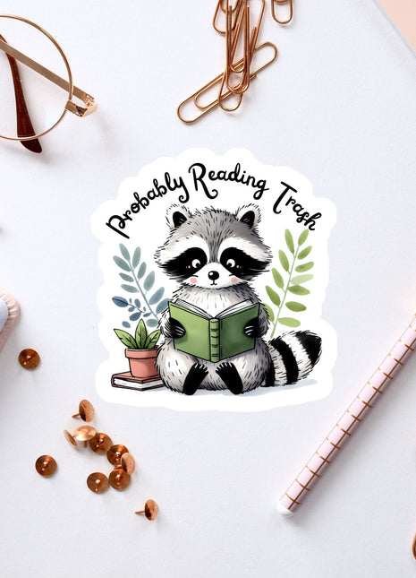 a sticker of a raccoon reading a book