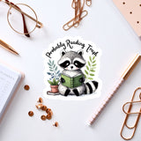 a sticker of a raccoon reading a book