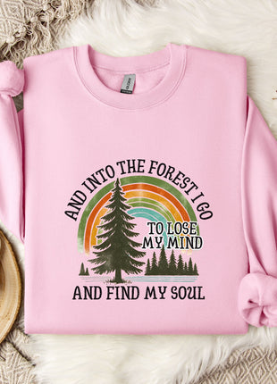 A pink sweatshirt with a graphic design of a forest and a rainbow, along with the text "AND INTO THE FOREST I GO TO LOSE MY MIND AND FIND MY SOUL".