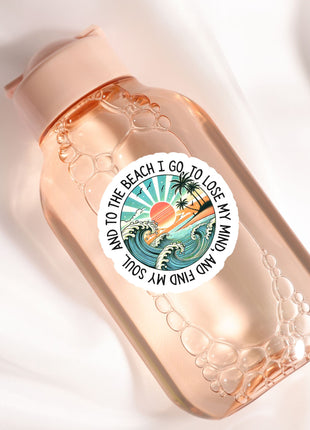 A clear glass bottle with a label featuring a beach scene and the text "I go to the beach I lose my mind".