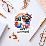 A sticker featuring a pug dog wearing a unicorn costume, with the text "I CAME I SAW I MADE IT AWKWARD" printed on it. The sticker is surrounded by various office supplies, such as a pen, a pair of glasses, and a notebook.