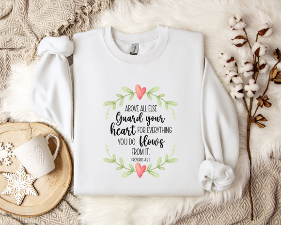 a white t-shirt with a printed message, a white mug, and some white flowers on a bed with a white blanket.