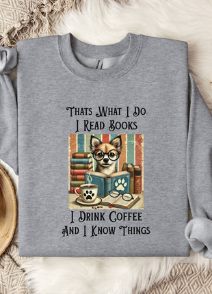 A gray sweatshirt with a printed design of a cat wearing glasses and surrounded by books, along with text that says "Thats what I do I read books I drink coffee and I know things".