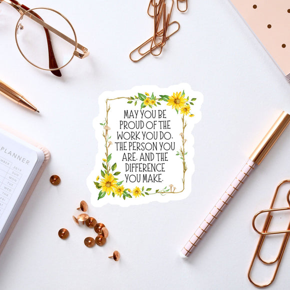 a sticker with a motivational quote, surrounded by various office supplies such as pens, a notebook, and a pair of glasses.