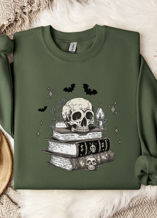 a green sweatshirt with a skull and bat design on it, along with a stack of books and a mug.