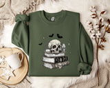 a green sweatshirt with a skull and bat design on it, along with a stack of books and a mug.