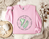 a pink sweater with a green sneaker on it