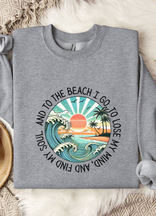 A gray sweatshirt with a graphic design depicting a beach scene, along with the text "And to the beach I go, I lose my soul and my mind".