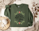 a green sweatshirt with a printed message, a white mug, and some white flowers on a bed with a white blanket.