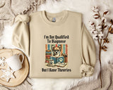a beige sweatshirt with a printed design of a cat wearing glasses and surrounded by books, along with the text "I'm Not Qualified To Diagnose But I Have Theories".