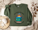a green sweatshirt with a graphic design depicting a trash can with flames coming out of it, accompanied by the text "It's fine, I'm fine Everything's fine".