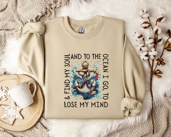 a beige sweatshirt with a graphic design of an anchor and waves, along with the text 