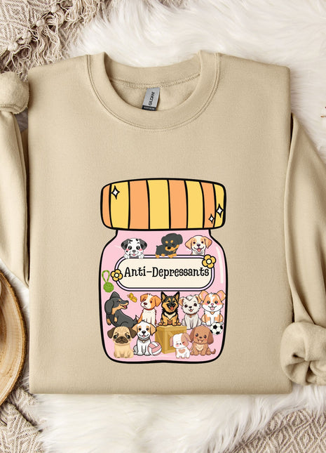 A beige sweatshirt with a graphic design of a jar containing various cartoon animals, including dogs, cats, and birds, along with the text "Ani-Depressants". The sweatshirt is placed on a white fur rug, and there is a mug and some cotton balls nearby.