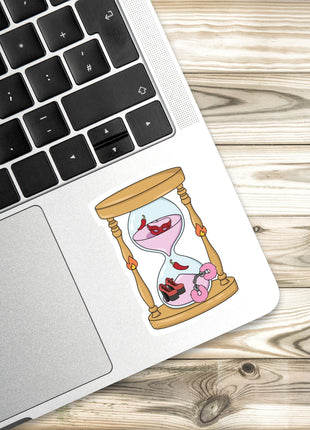 a sticker of a sand timer with a pink and red design on a laptop keyboard.