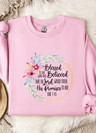 A pink sweatshirt with a floral design and text printed on it, placed on a white fur rug.