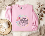 A pink sweatshirt with a floral design and text printed on it, placed on a white fur rug.