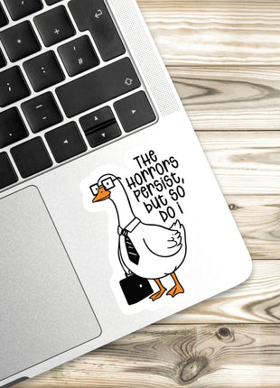 A sticker of a cartoon goose wearing a tie and glasses, sitting on a laptop keyboard.