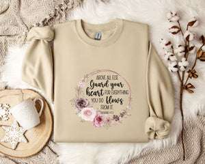 a beige sweatshirt with a floral design and text printed on it, along with a coffee mug and some decorative elements such as a snowflake and a branch.