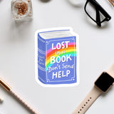 a sticker with a book and a rainbow, along with some office supplies such as a pen, a watch, and a pair of glasses.