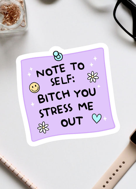 a purple sticky note with a humorous message, surrounded by various office supplies and accessories such as a pair of glasses, a pen, and a watch.