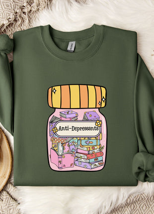 a green sweatshirt with a colorful graphic design depicting a jar with various objects inside, including a book and a flower. The text on the sweatshirt reads "Ani-Depressants".