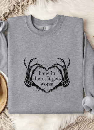a gray sweatshirt with a graphic design on it, along with a mug, a branch of cotton bolls, and a blanket.