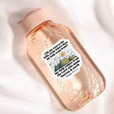 A pink bottle with a sticker featuring a mountain landscape and a Bible verse.