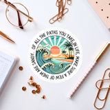 a sticker with a beach scene, surrounded by various office supplies such as pens, a notebook, and a pair of glasses.